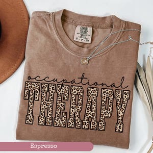 May include: Espresso brown t-shirt with a leopard print graphic that says "occupational therapy".