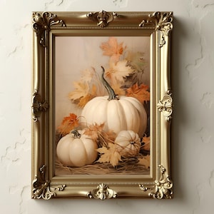 May include: A framed artwork featuring a still life of white pumpkins and autumn leaves. The pumpkins are arranged with fall foliage in a gold ornate frame. The artwork evokes a harvest theme.