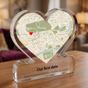 May include: A heart-shaped clear acrylic plaque featuring a printed map of London with a red heart icon marking a specific location. The base includes the black text "Our first date" followed by "Kegworth park, KEGWORTH 53.4505°- N -2.2500°W".