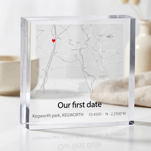 Può includere: Un blocco acrilico trasparente con una mappa stampata di Kegworth e un'icona a forma di cuore rosso che segna una posizione specifica. Sotto la mappa, il testo recita Our first date, Kegworth park, KEGWORTH e le coordinate 53.4505° N - 2.2500° W.