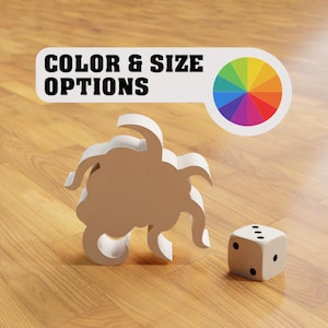 Op de afbeelding: Wit 3D-geprint speelgoed in de vorm van een wolk met zes poten. Het speelgoed ligt op een houten vloer naast een witte dobbelsteen met zwarte stippen. Een kleurencirkel bevindt zich op de achtergrond met de tekst "COLOR & SIZE OPTIONS".