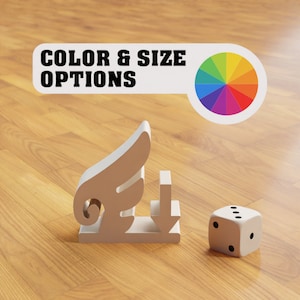 Può includere: Un designo a forma di ala e freccia argentato con un dado bianco su una superficie in legno. Il testo "COLOR & SIZE OPTIONS" è sopra il design con una ruota dei colori a destra.