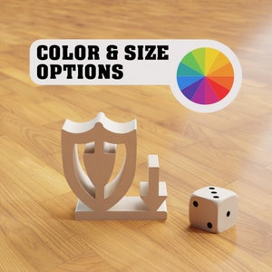 Op de afbeelding: Een wit schild- en pijlpictogram met een witte dobbelsteen op een houten oppervlak. De tekst "COLOR & SIZE OPTIONS" is zichtbaar boven het pictogram. Een regenboogkleurenwiel is zichtbaar in de rechterbovenhoek.