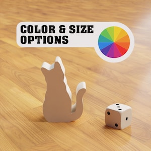 Puede incluir: Una figurita de gato blanca sentada en un suelo de madera con un dado blanco y una rueda de colores con el texto "COLOR & SIZE OPTIONS" encima.