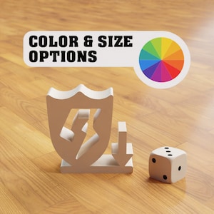 Puede incluir: Un escudo blanco con un rayo dentro, una flecha blanca apuntando hacia abajo y un dado blanco de seis caras con puntos negros sobre una superficie de madera. El texto "COLOR & SIZE OPTIONS" está por encima del escudo y la flecha. Una rueda de colores con colores arcoíris está a la derecha del texto.