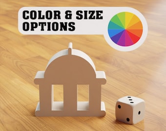 May include: A white model of a building with a dome roof and three columns. A color wheel with a rainbow of colors is above the building. The text "COLOR & SIZE OPTIONS" is on a white banner above the color wheel. A white die with black dots is on the right side of the building.