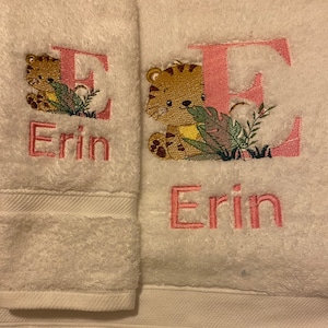 Puede incluir: Dos toallas blancas con bordados rosas. Las toallas presentan la letra "E" con una ilustración de tigre y el nombre "Erin" bordado en cada toalla.