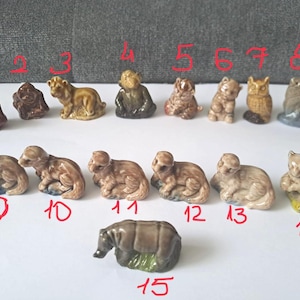 Op de afbeelding: Een verzameling kleine keramische dierenbeeldjes, waaronder een leeuw, een aap, een uil en een eekhoorn. De beeldjes zijn beschilderd in verschillende tinten bruin, beige en grijs. Elk beeldje is rood genummerd.