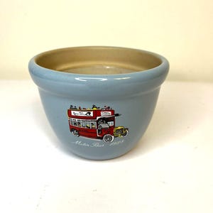 Könnte beinhalten: Eine hellblaue Keramikschale mit beigem Innenraum. Die Schale zeigt eine Illustration eines roten Doppeldeckerbusses mit dem Text "Motor Bus 1928". Ein gelbes Oldtimer-Auto ist ebenfalls abgebildet.
