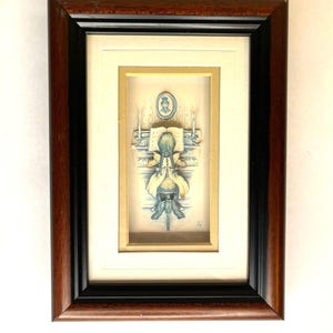 Puede incluir: Obra de arte enmarcada con una ilustración detallada de una persona tocando un instrumento musical. La obra de arte está en un marco rectangular con un acabado de madera marrón oscuro y un borde interior negro. La ilustración es en tonos azules y beige.