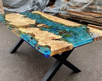 May include: A large wooden table with a blue and green epoxy resin top. The table has a black metal X-shaped base.