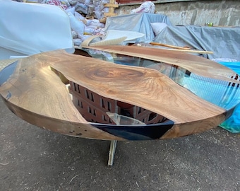 May include: A round wooden table with a black and blue epoxy resin inlay. The table has a unique, natural wood grain pattern and a single, silver metal leg.