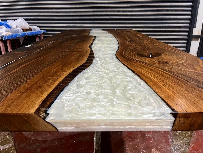 Puede incluir: Primer plano de una mesa de madera con un r&iacute;o de resina blanca que recorre el centro. La madera es de un color marr&oacute;n intenso y la resina es lisa y brillante.