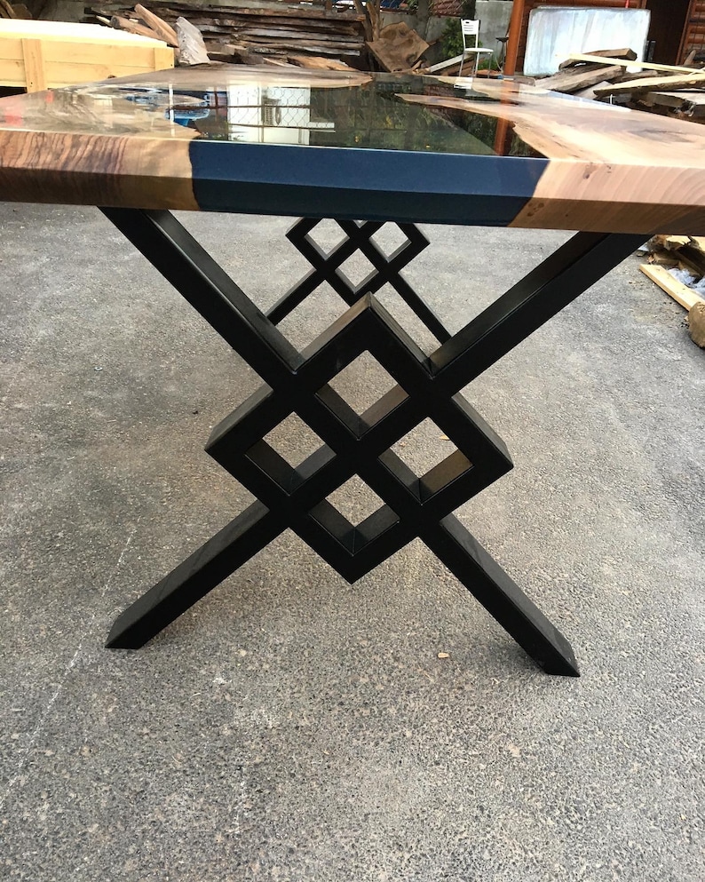 Puede incluir: Una mesa de madera con una tapa de resina epoxi negra y una base de metal negro geom&eacute;trica. La mesa tiene un acabado de madera natural.