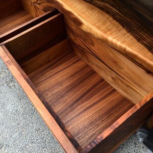 May include: A wooden cabinet with two open drawers. The drawers are made of wood with a dark brown stain. The cabinet has a black painted exterior.