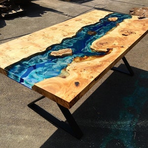 May include: A wooden table with a blue and green epoxy resin river running through the center. The table has black metal legs.