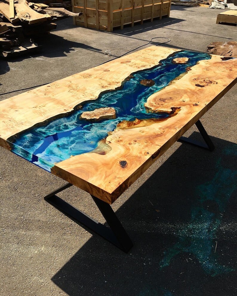 May include: A wooden table with a blue and green epoxy resin river running through the center. The table has black metal legs.