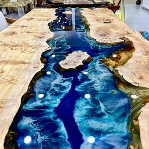 May include: A wooden table with a blue and white epoxy resin river running through the center. The resin has a swirling pattern and is very glossy.