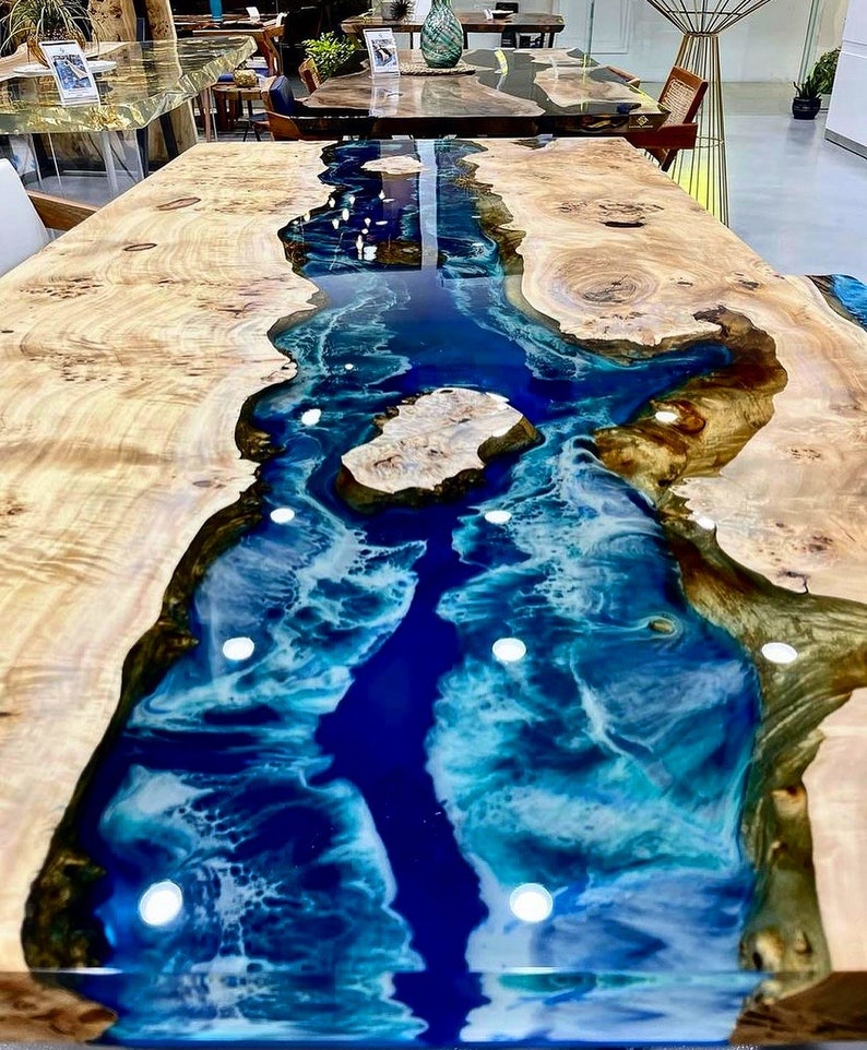 May include: A wooden table with a blue and white epoxy resin river running through the center. The resin has a swirling pattern and is very glossy.
