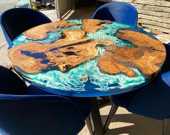 May include: A round wooden table with a blue and white epoxy resin top. The table is surrounded by four blue velvet chairs.