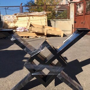 Puede incluir: Base de mesa de metal negro con un dise&ntilde;o geom&eacute;trico. La base est&aacute; hecha de cuatro piezas de metal que se cruzan para formar una forma cuadrada. La base est&aacute; envuelta en pl&aacute;stico.