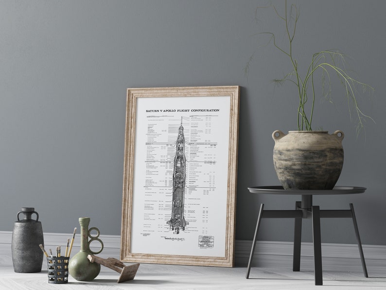 May include: A black and white diagram of the Saturn V Apollo flight configuration, showing the different stages of the rocket. The diagram is framed in a light wood frame and is hanging on a gray wall.