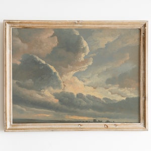 Op de afbeelding: Een ingelijst schilderij dat een landschap met een bewolkte lucht afbeeldt. De wolken zijn een mix van wit, grijs en lichtblauw en vullen het grootste deel van het doek. De horizon is zichtbaar aan de onderkant van het schilderij, en er zijn een paar kleine bomen of gebouwen in de verte.