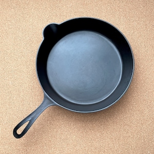 May include: A black cast iron skillet with a long handle. The skillet is empty and has a smooth, slightly worn surface.