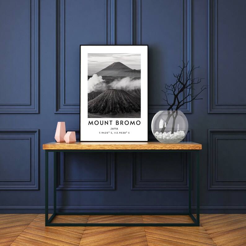 K&ouml;nnte beinhalten: Schwarzwei&szlig;foto des Mount Bromo auf Java, Indonesien. Das Bild zeigt einen Vulkan mit Rauch, der aus dem Krater aufsteigt. Der Text "MOUNT BROMO JAVA 7.9425&deg; S, 112.9350&deg; E" ist unter dem Bild gedruckt.