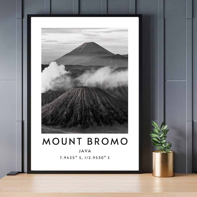 K&ouml;nnte beinhalten: Schwarzwei&szlig;foto des Mount Bromo, eines Vulkans in Java, Indonesien. Der Vulkan ist von Wolken und Nebel umgeben. Der Text "MOUNT BROMO JAVA 7.9425&deg; S, 112.9530&deg; E" ist unter dem Bild gedruckt.