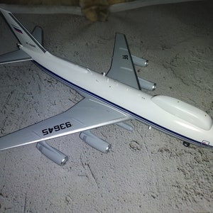 May include: A white model aeroplane with blue accents and the text "RF" and "63645" on the wings. The aeroplane has a large, white dome on top.