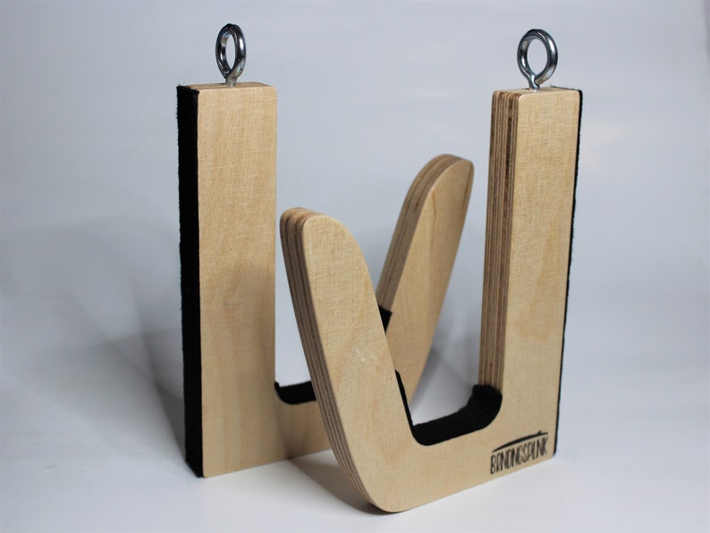 May include: Two wooden surfboard racks with a natural finish. Each rack has a U-shaped design with a black padded interior and a metal ring at the top for hanging. The brand name "BINDINGSINK" is visible on one rack.
