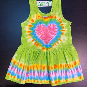 May include: Green tie-dye sleeveless dress with a pink heart design. The dress has a ruffled hem and says "SIZE 4T" on the tag.