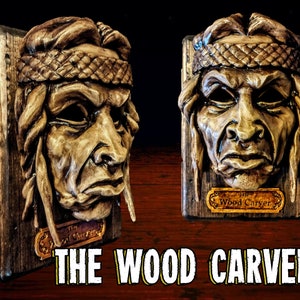 May include: A wall-mounted wood carving depicting a person with a braided headband, set on a rectangular wooden plaque. A small gold-coloured nameplate at the bottom reads The Wood Carver. The text THE WOOD CARVER appears in large white letters.