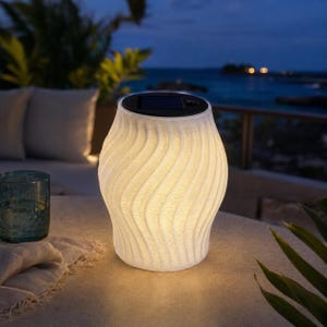 May include: A white, wavy-textured, cylindrical solar-powered lamp emitting a warm, soft glow. The top of the lamp features a flat, black circular solar panel with a small button, providing a contrast to the translucent, ribbed body.
