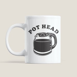 May include: White ceramic coffee mug with a black illustration of a coffee pot and the text "POT HEAD".