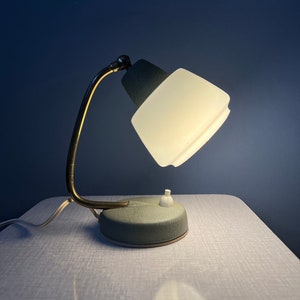 May include: A vintage green and brass desk lamp with a white frosted glass shade. The lamp has a single switch on the base.