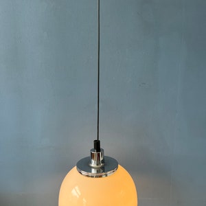 May include: A white, dome-shaped pendant light fitting with a chrome finish. The light is hanging from a black cord.