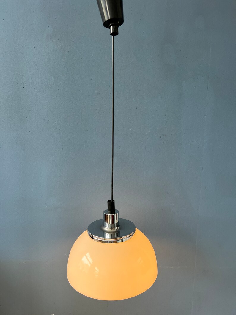 May include: A white, dome-shaped pendant light fitting with a chrome finish. The light is hanging from a black cord.