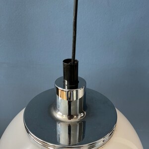 May include: Close-up of a white globe pendant light fitting with a chrome metal base and a black wire.