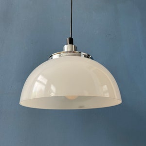 May include: A white dome-shaped pendant light fixture with a chrome trim hangs from a black cord against a blue wall.