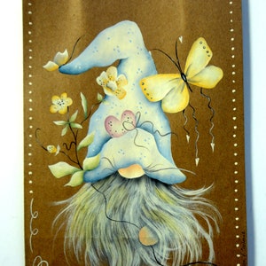 May include: A hand-painted brown paper bag with a blue gnome wearing a blue hat with white polka dots and a white beard. The gnome is surrounded by yellow flowers and a yellow butterfly with black markings.