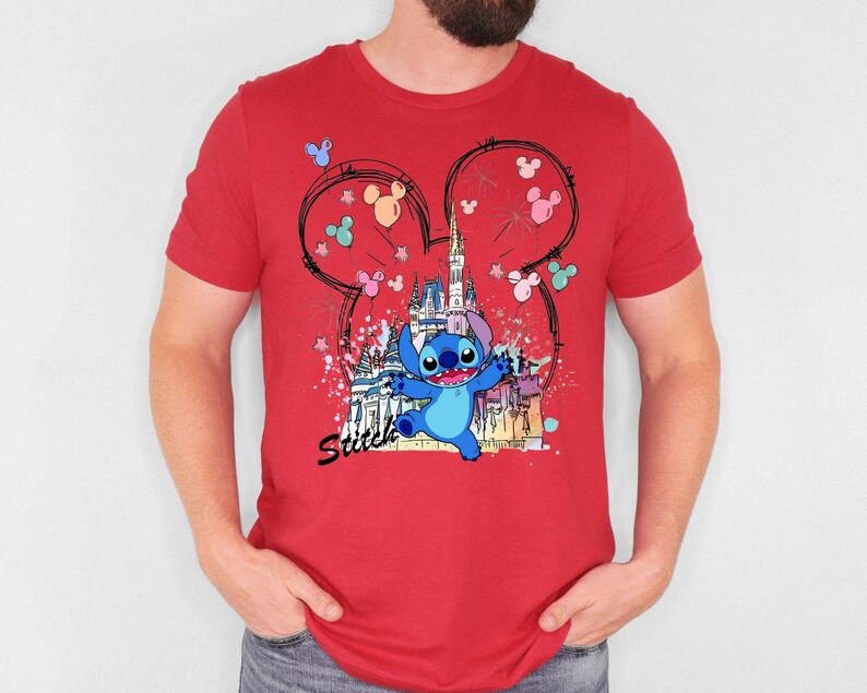 May include: Red t-shirt featuring a cartoon illustration of Stitch from Lilo & Stitch. The design includes a castle, Mickey Mouse ears, and the word "Stitch". The shirt is a crew neck style.