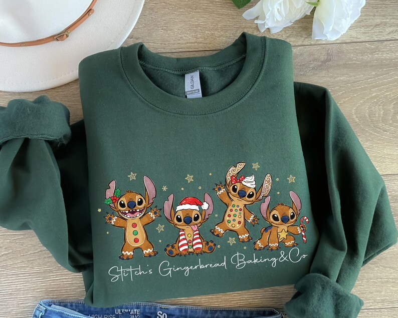 Puede incluir: Una sudadera verde oscuro con un gr&aacute;fico de cuatro personajes de jengibre, con el texto Stitch's Gingerbread Baking & Co. Los personajes tienen poses festivas, con accesorios como un gorro de Pap&aacute; Noel y un bast&oacute;n de caramelo.