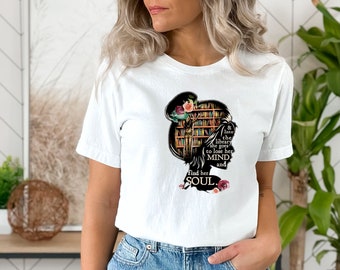 May include: White t-shirt featuring a silhouette of a woman's head filled with a library scene and floral accents. Text reads "& Into the library she goes to lose her MIND and find her SOUL."