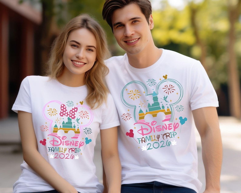 May include: White t-shirts with a colorful Disney design. The design includes a castle, fireworks, and the text "Disney Family Trip 2020". One shirt features a Minnie Mouse bow. The other shirt has a Mickey Mouse design.