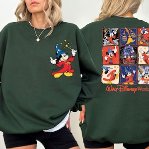 May include: Dark green sweatshirt featuring a Mickey Mouse graphic on the front and back. The front graphic shows Mickey as a sorcerer with a wand. The back has a grid of Mickey Mouse images and the words "Walt Disney World".