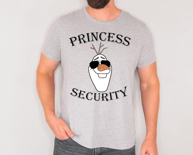 Pu&ograve; includere: T-shirt grigio chiaro con le parole "PRINCESS SECURITY" sopra e sotto un pupazzo di neve dei cartoni animati con occhiali da sole e un naso a carota. La maglietta &egrave; a maniche corte.