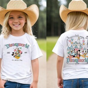 May include: White t-shirt with a colourful Disney World graphic on the front and back. The front features Mickey, Minnie, Donald, and Daisy Duck, with the text "Disneyworld EST 1971 FLORIDA". The back shows the Disney World castle and characters.