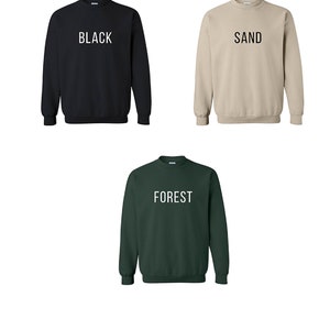 May include: Unisex sweatshirt color chart with three sweatshirts in black, sand, and forest green. The chart shows the size and measurements in inches for each size: S, M, L, XL, and 2XL.